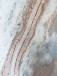 Homeowner inspecting kitchen countertops made of quartz and granite in a well-lit residential kitchen.