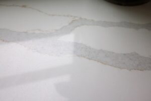 A person wiping a natural stone kitchen countertop with a soft cloth.