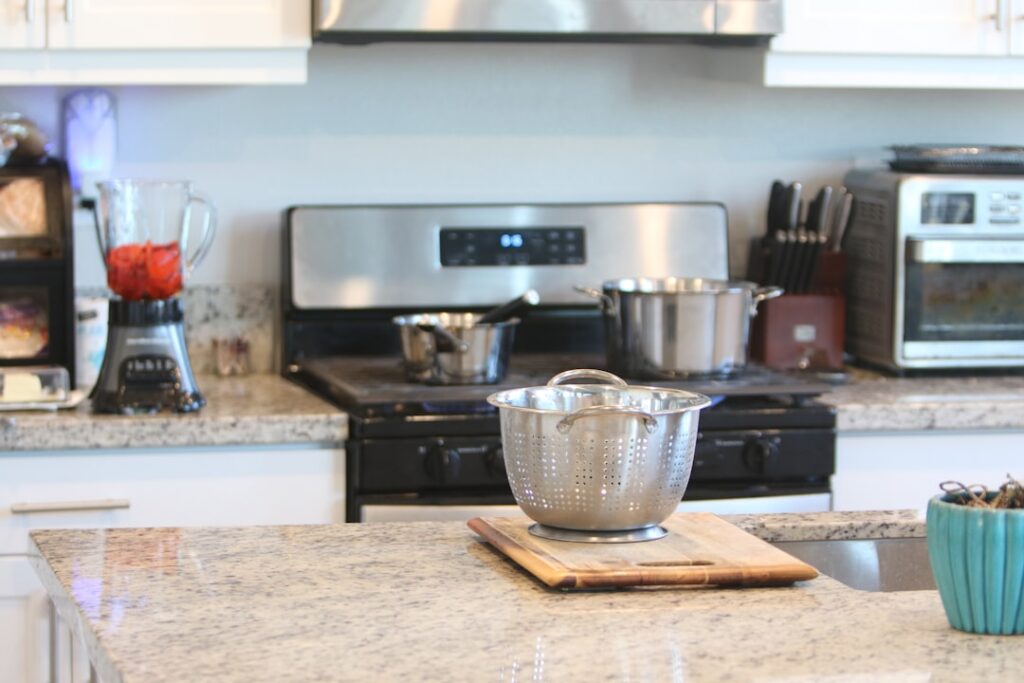 A person wearing gloves gently wiping a granite kitchen countertop with a damp cloth.