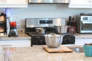 A person wearing gloves gently wiping a granite kitchen countertop with a damp cloth.